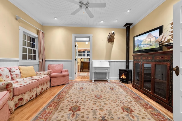 living room featuring a wood stove, hardwood / wood-style flooring, ceiling fan, crown molding, and wooden ceiling