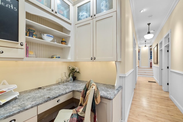 381 Lakeside Blvd, Lakeside, MT 59922 - kitchen featuring crown molding, light wood-style floors, light stone countertops, a wainscoted wall, and glass insert cabinets