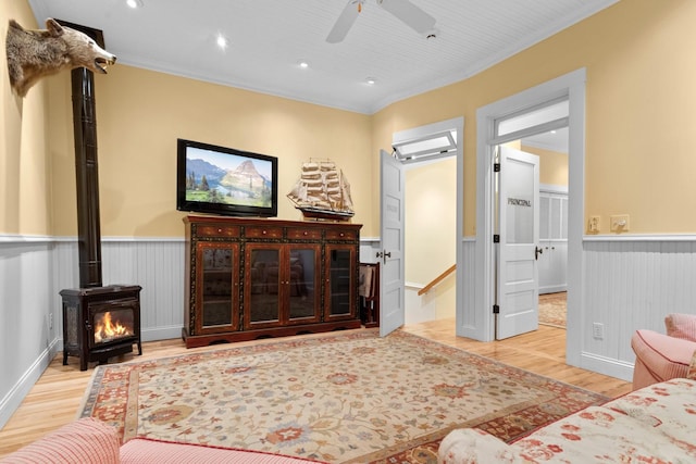 living room featuring crown molding, a wood stove, and light wood-type flooring