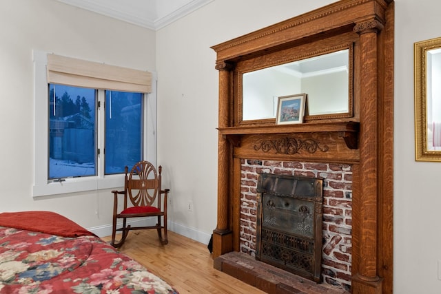 bedroom with crown molding, hardwood / wood-style floors, and a brick fireplace