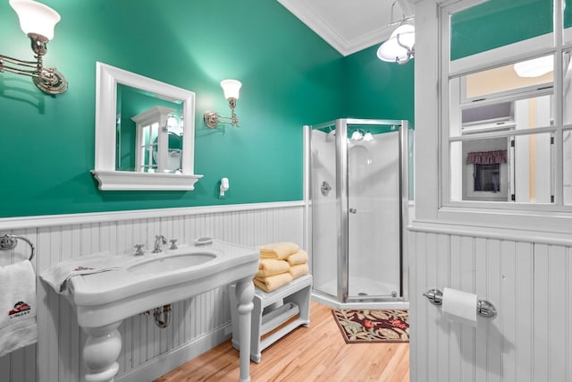 bathroom with hardwood / wood-style flooring, ornamental molding, and a shower with shower door