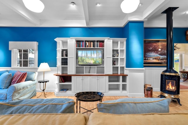 living room with beam ceiling, hardwood / wood-style flooring, and a wood stove