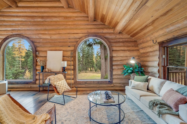 living room with wood ceiling, wood-type flooring, lofted ceiling with beams, a healthy amount of sunlight, and log walls