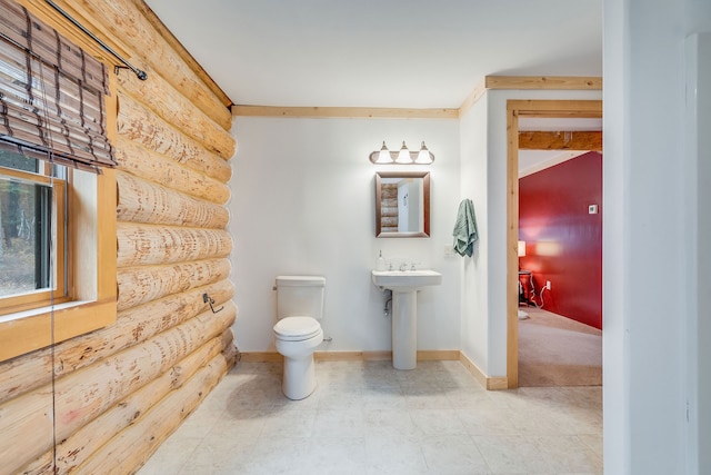 bathroom featuring sink, log walls, and toilet