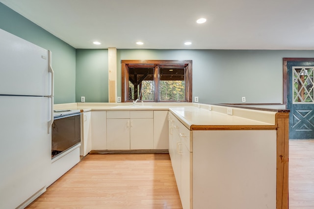 kitchen featuring light hardwood / wood-style floors, sink, white appliances, and kitchen peninsula