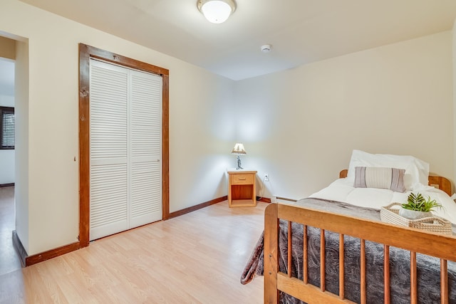 bedroom featuring hardwood / wood-style flooring, baseboard heating, and a closet