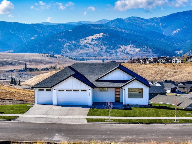 exterior space with a garage, a mountain view, and a front lawn