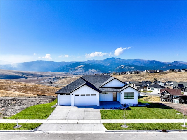 view of front of property featuring a mountain view, a front yard, and a garage