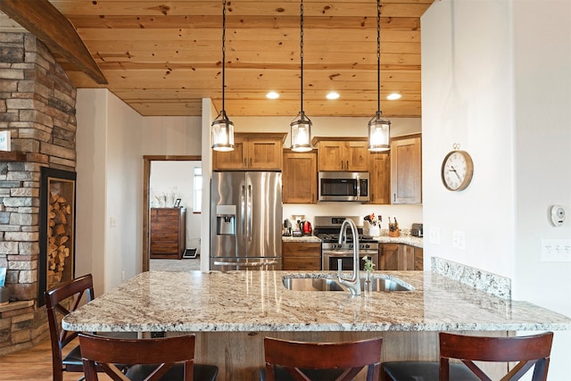 kitchen featuring kitchen peninsula, wood-type flooring, sink, pendant lighting, and appliances with stainless steel finishes