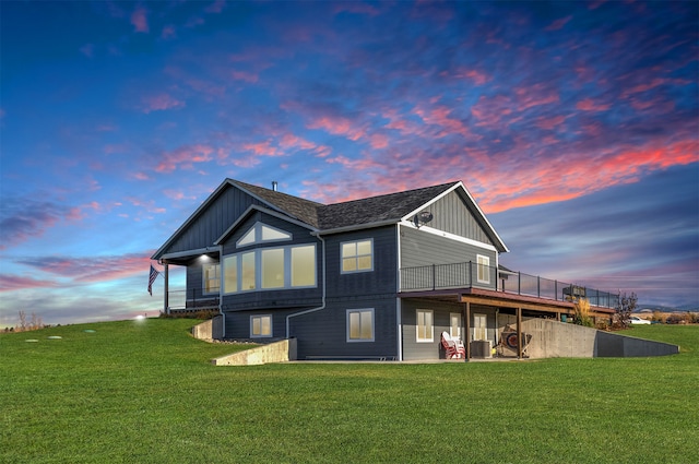 back house at dusk featuring a yard, a deck, and central air condition unit