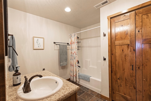 bathroom with vanity, a textured ceiling, and shower / bath combination with curtain