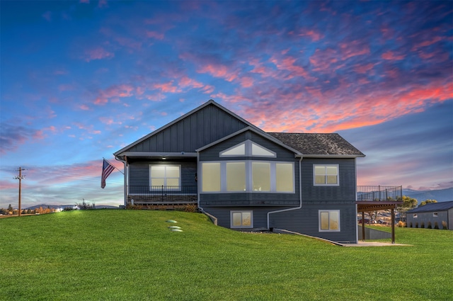 back house at dusk featuring a lawn