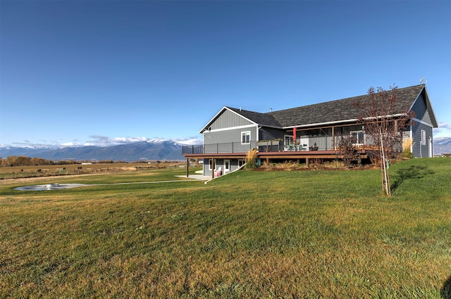 rear view of house with a yard and a deck with mountain view