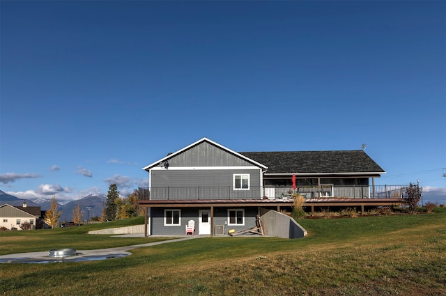 rear view of house featuring a lawn and a deck with mountain view