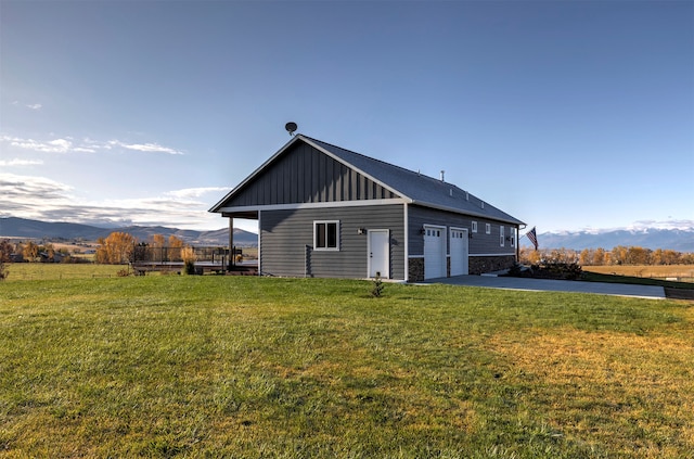 rear view of house featuring a mountain view, a yard, a garage, and a rural view