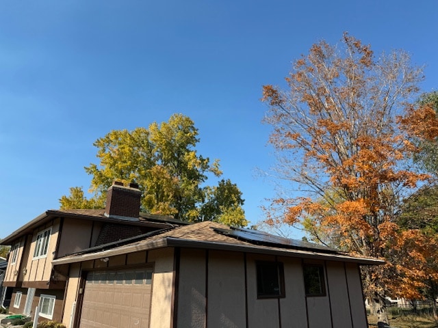 view of property exterior featuring solar panels and a garage