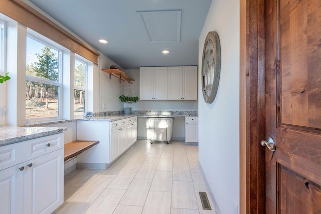 kitchen with light tile patterned floors, light stone countertops, and white cabinets