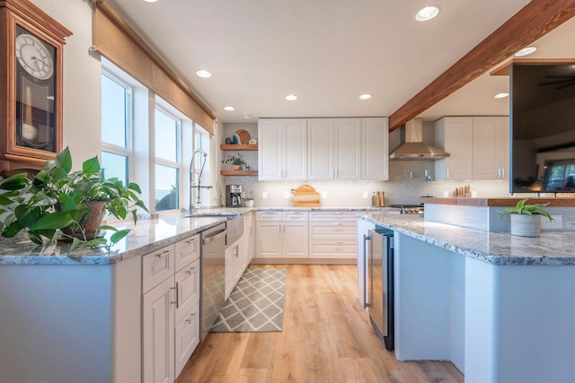 kitchen featuring stainless steel dishwasher, wall chimney exhaust hood, light stone countertops, and white cabinets