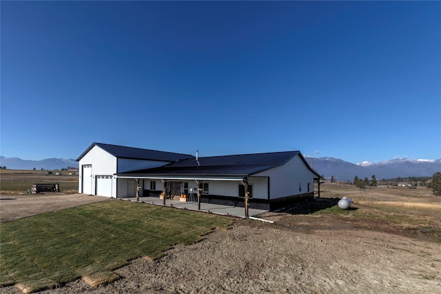 view of front of home featuring a mountain view, a front yard, a garage, and a rural view