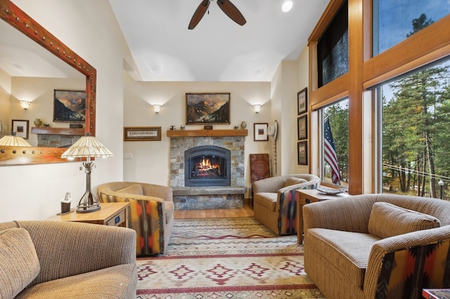 living room with a stone fireplace, hardwood / wood-style floors, ceiling fan, and vaulted ceiling