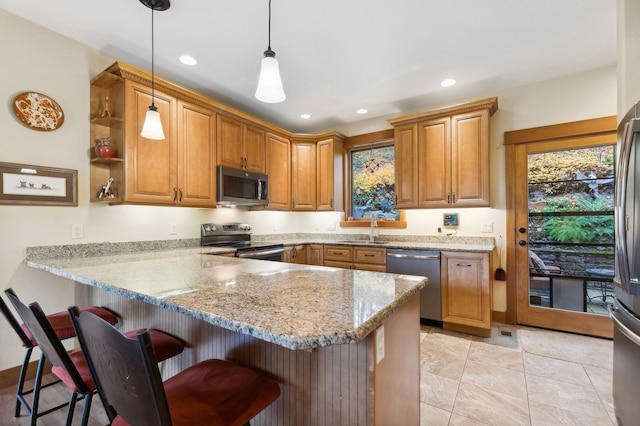 kitchen featuring kitchen peninsula, appliances with stainless steel finishes, a breakfast bar area, and decorative light fixtures