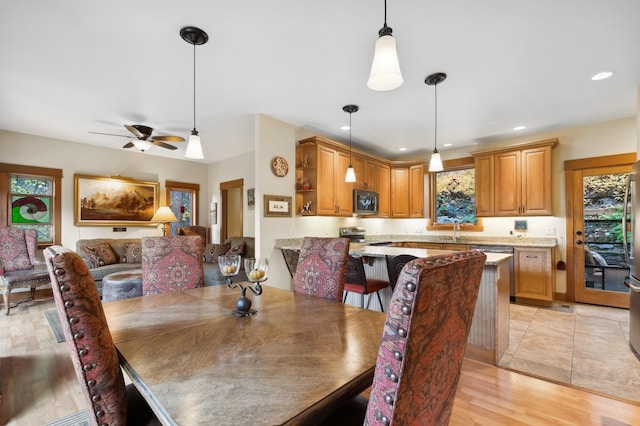 dining room featuring ceiling fan, sink, and light wood-type flooring