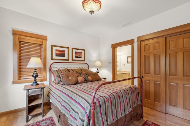 bedroom with light hardwood / wood-style floors and ensuite bath