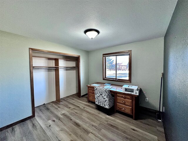 bedroom featuring a closet, a textured ceiling, and light hardwood / wood-style flooring