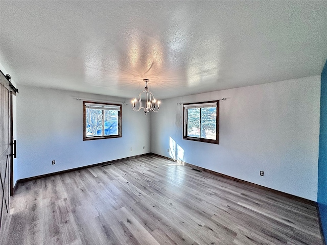 spare room featuring a textured ceiling, light hardwood / wood-style flooring, and a barn door