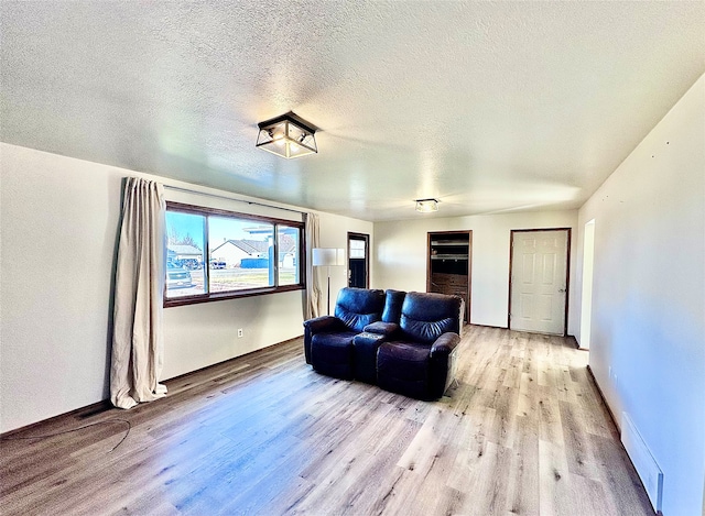 cinema room featuring a textured ceiling, a baseboard radiator, and light wood-type flooring