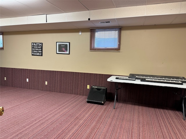 miscellaneous room featuring carpet, a paneled ceiling, and wood walls