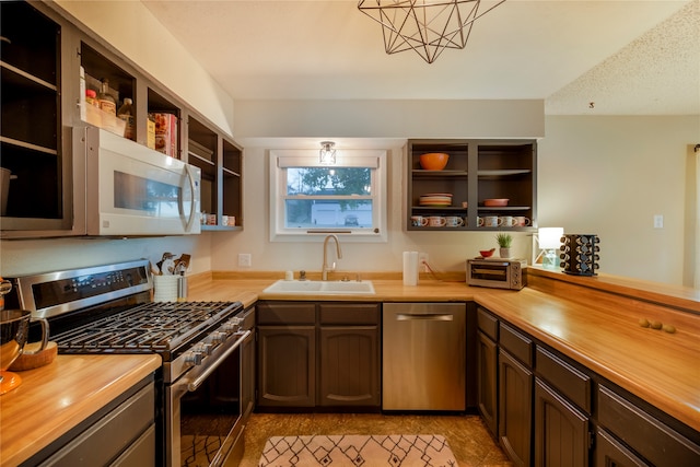 kitchen with stainless steel appliances, butcher block counters, sink, and a textured ceiling