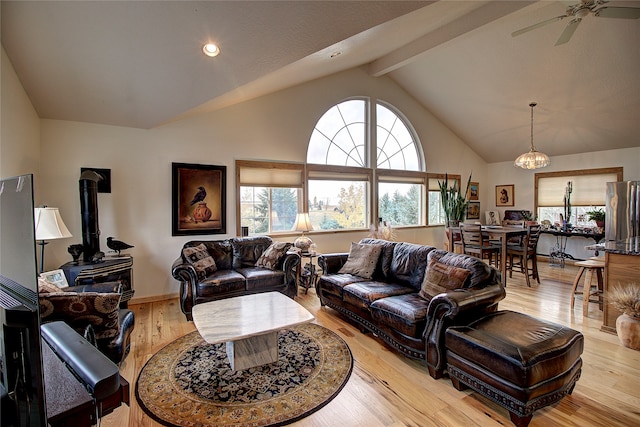 living room featuring lofted ceiling with beams, ceiling fan, light wood-type flooring, and a wood stove