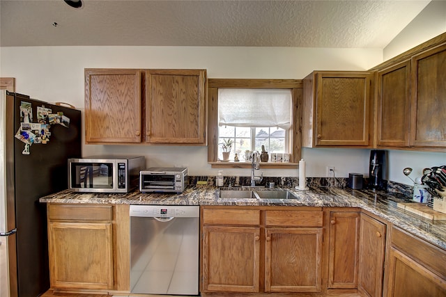 kitchen with sink, vaulted ceiling, tile patterned flooring, a textured ceiling, and appliances with stainless steel finishes