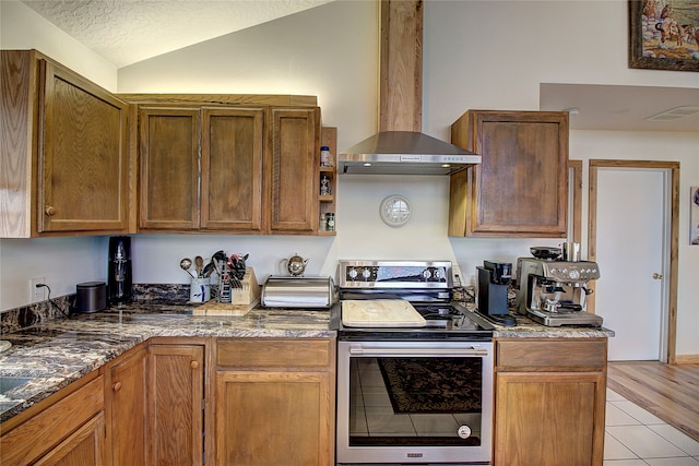 kitchen featuring lofted ceiling, stainless steel range with electric cooktop, light wood-type flooring, a textured ceiling, and extractor fan