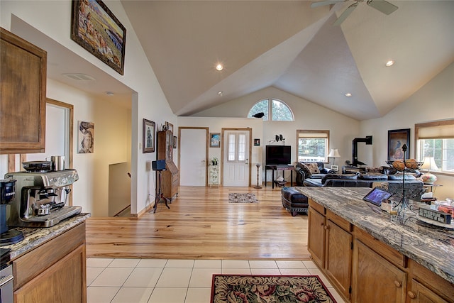 kitchen featuring ceiling fan, high vaulted ceiling, and light hardwood / wood-style flooring