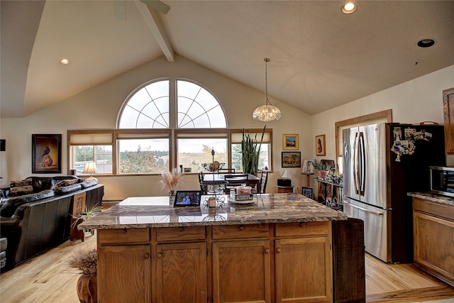 kitchen featuring appliances with stainless steel finishes, a center island, light hardwood / wood-style flooring, vaulted ceiling with beams, and hanging light fixtures