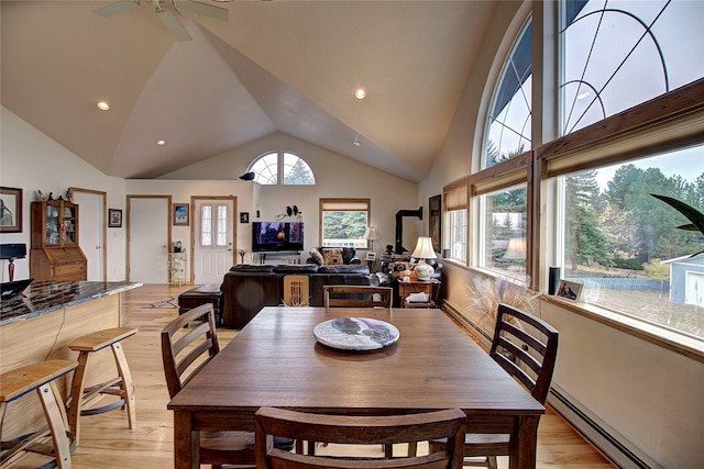 dining room with ceiling fan, light wood-type flooring, high vaulted ceiling, and a baseboard radiator