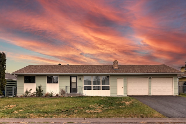 ranch-style home featuring a garage and a lawn