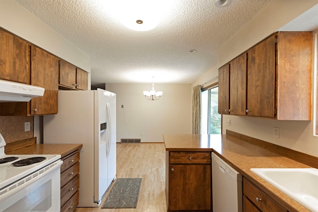 kitchen featuring white appliances, range hood, decorative light fixtures, a textured ceiling, and light hardwood / wood-style floors