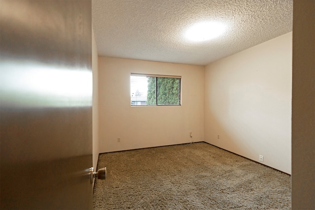 carpeted empty room with a textured ceiling