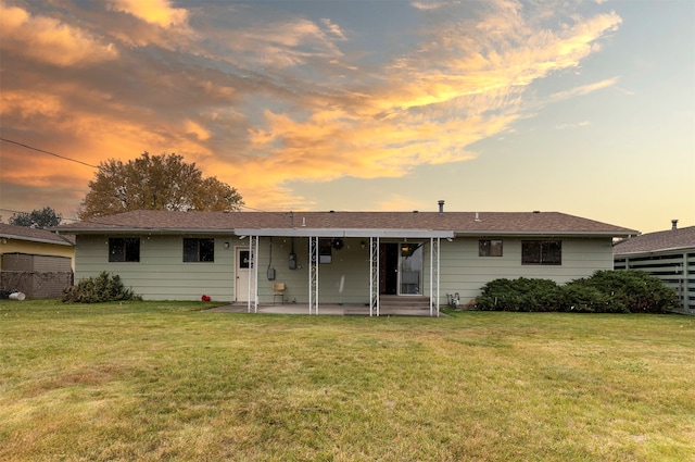 back house at dusk featuring a yard and a patio