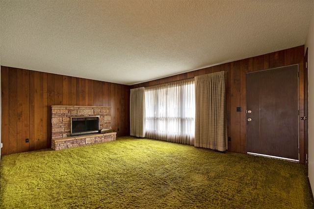 unfurnished living room featuring dark carpet, a textured ceiling, and wood walls