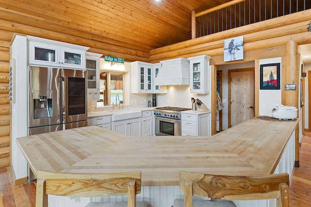 2197 W Tower Rd, Saltese, MT 59867 - kitchen with custom exhaust hood, a sink, wooden ceiling, stainless steel appliances, and rustic walls