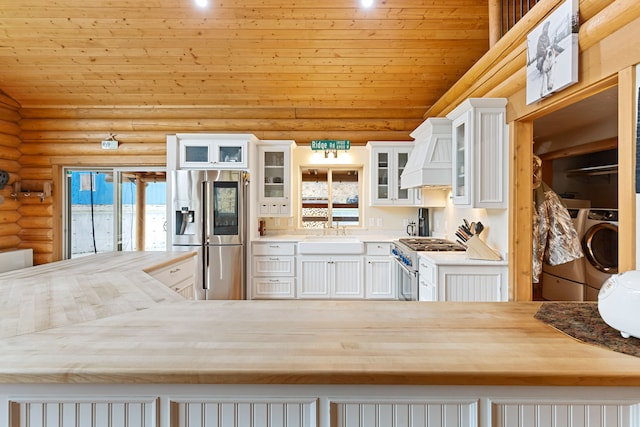2197 W Tower Rd, Saltese, MT 59867 - kitchen with appliances with stainless steel finishes, log walls, washer / dryer, a sink, and custom exhaust hood