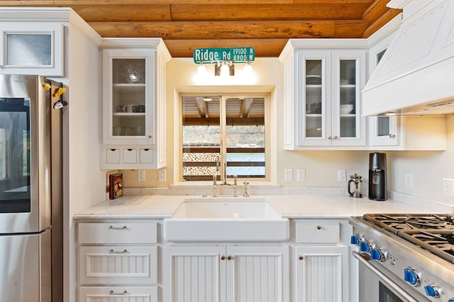 2197 W Tower Rd, Saltese, MT 59867 - kitchen featuring appliances with stainless steel finishes, custom range hood, a sink, white cabinetry, and glass insert cabinets