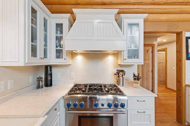 2197 W Tower Rd, Saltese, MT 59867 - kitchen featuring stainless steel stove, premium range hood, wood finished floors, white cabinets, and light stone countertops
