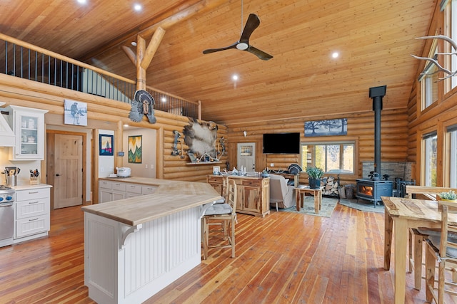 2197 W Tower Rd, Saltese, MT 59867 - kitchen featuring a wood stove, high vaulted ceiling, wood ceiling, log walls, and white cabinets
