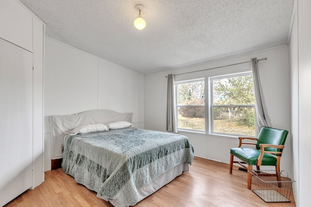 bedroom with light hardwood / wood-style flooring and a textured ceiling