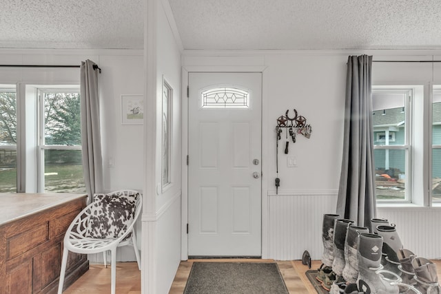 foyer entrance with wood walls, a textured ceiling, and light wood-type flooring